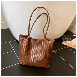 Macro detail of the brown woven leather texture and fine craftsmanship on the tote bag