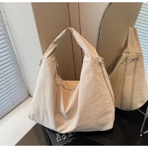 Detail of off-white hobo bag with wrinkled texture and side zipper on dark table