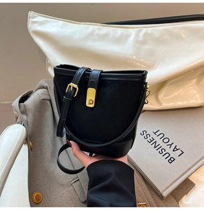 Gros plan du sac seau matelassé noir avec boucle dorée et détails en cuir lisse