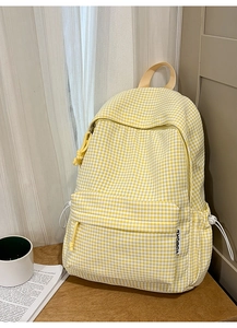Détail du sac à dos à carreaux jaunes montrant la poche latérale et l'étiquette tissée