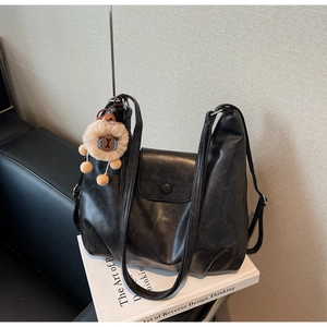 Dettaglio della borsa tote nera in pelle con patta e ciondolo a forma di animale