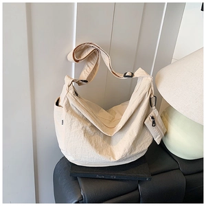 Macro shot of beige crinkled nylon hobo bag with adjustable strap and small zip pouch