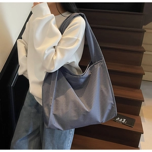 Détail du grand sac cabas en toile à carreaux porté à l'épaule par un mannequin