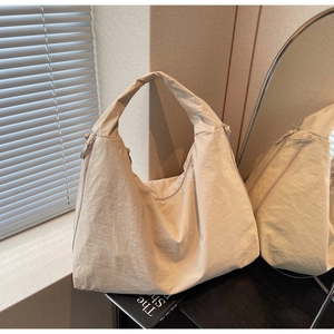 Detail view of a beige minimalist hobo bag with textured fabric and seamless handle