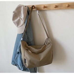 Detailed close-up of khaki nylon crossbody bag texture with adjustable strap on wooden hook