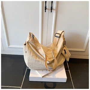 Detailed view of beige ruched dumpling bag with adjustable strap and side coin pouch