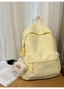 Détail d'un sac à dos à carreaux jaunes avec pendentif étoile sur une table en bois