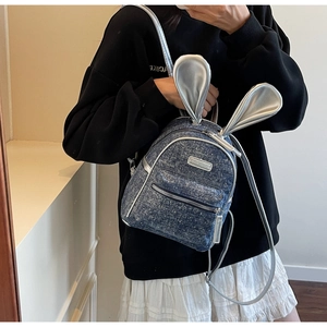 Mini denim backpack with silver bunny ears detail shown on a model for size scale
