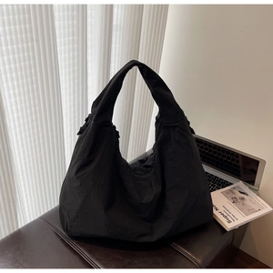 Detailed view of the large black nylon hobo tote bag on a modern leather bench
