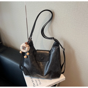 Dettaglio borsa hobo in pelle nera con cerniera superiore e ciondolo a forma di agnello