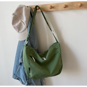 Detail of green nylon hobo bag featuring white double zippers and adjustable strap