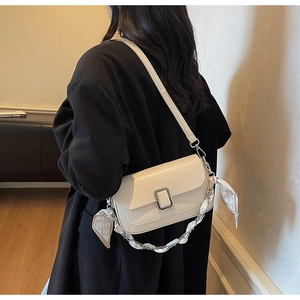 Detail of off-white crocodile texture crossbody bag with silver buckle and silk scarf strap