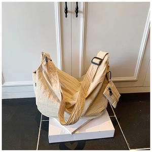 Detail view of large beige crossbody bag with pleated texture and mini zipper pouch