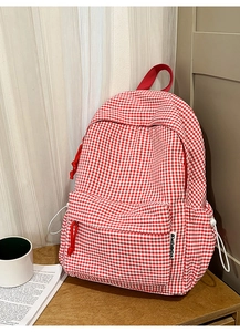 Vue détaillée du sac à dos en toile à carreaux vichy rouge et blanc avec poche avant et logo