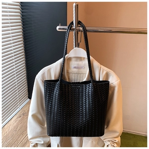 Close-up of the black woven texture and leather handle on the large tote bag