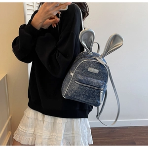 Close-up of denim backpack featuring sparkling sequins and oversized silver bunny ears