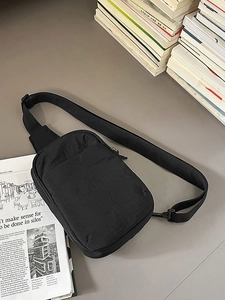 Bolso de pecho minimalista de nailon negro con correa ajustable sobre fondo profesional