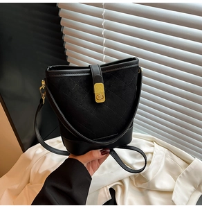 Détail d'un sac seau matelassé avec fermoir rotatif doré et finitions en cuir lisse