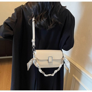 Detail of cream crossbody bag with croc texture and silk scarf handle on model