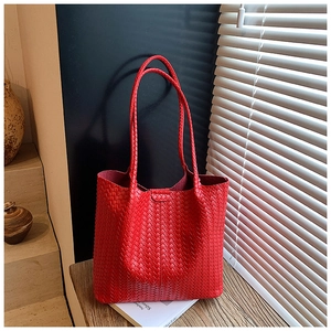 Detail of red woven leather tote bag featuring intricate texture and thin double shoulder straps