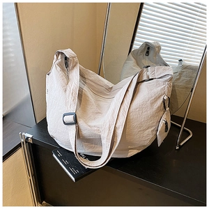 Detail of beige wrinkled nylon crescent bag with adjustable strap and side pouch