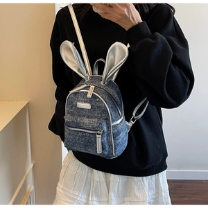 Close-up of denim backpack featuring silver rabbit ears and starry white speckle design