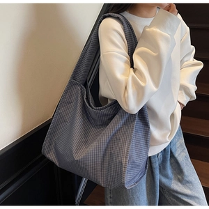 Détail du grand sac cabas à carreaux bleu porté avec une tenue de style décontracté