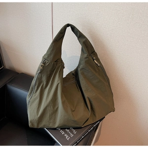 Detail view of the olive green canvas tote bag with smooth metal zipper and pleated texture