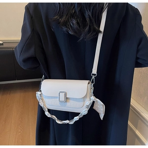 Detail of off-white crossbody bag with crocodile texture and silk scarf chain strap