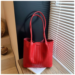 Detail of red woven leather tote bag showing intricate intrecciato texture on wood