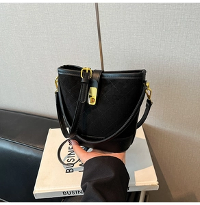 Gros plan du sac seau noir matelassé avec des détails métalliques dorés chic