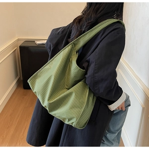 Vue détaillée du sac cabas en toile à carreaux verts porté par un mannequin en salle