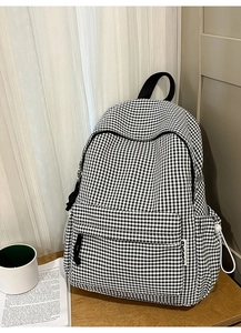 Détail du sac à dos à carreaux noir et blanc avec étiquette RKOBN et poches latérales
