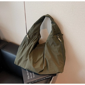 Detail of olive green nylon crescent tote bag showing natural pleats and side zipper