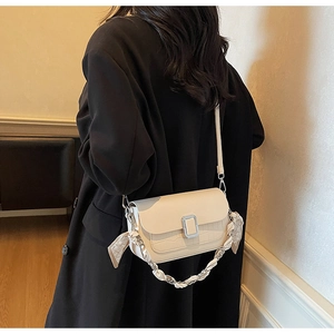 Detail of cream crossbody bag with crocodile texture, silver buckle and silk scarf