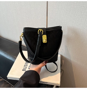 Détail du sac seau noir matelassé avec boucle dorée et texture en daim