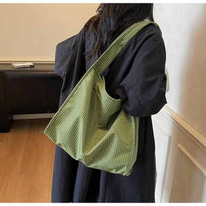 Grand sac cabas à carreaux verts avec large bandoulière dans une pièce minimaliste