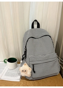 Détail du sac à dos étudiant à carreaux avec un porte-clés étoile sur bureau en bois