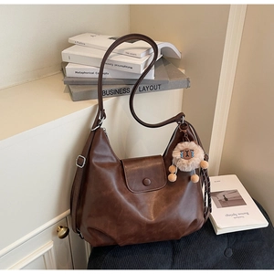 Dettaglio della borsa hobo vintage marrone scuro con trama opaca e ciondolo in peluche