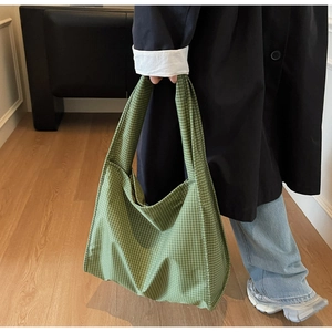 Détail du grand sac cabas à carreaux verts montrant la texture en toile sur modèle