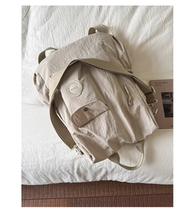 Detail of light beige nylon backpack showing the front pocket with N 05 logo and zipper
