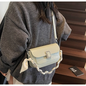 Detail of light green crossbody bag featuring crocodile texture and silk scarf chain
