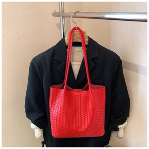 Detailed close-up of red woven texture and long handles on a large fashion tote bag