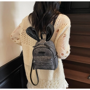 Close-up of cute rabbit ear denim backpack with silver zipper and metal stud details