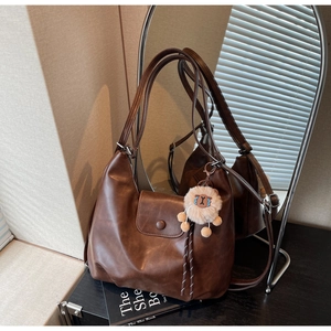 Dettaglio della borsa tote in pelle marrone scuro con ciondolo e patta magnetica