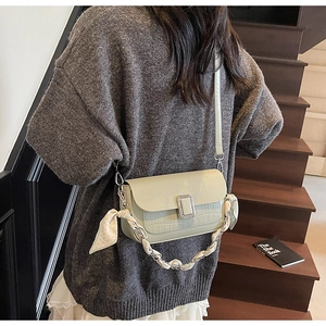 Detail of light green square crossbody bag featuring crocodile texture and silk scarf chain