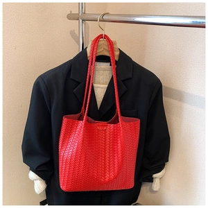 Detailed view of red woven leather tote bag texture and long shoulder strap