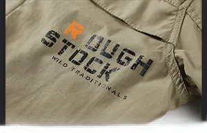 Detail of khaki outdoor jacket with industrial print and orange R logo patch