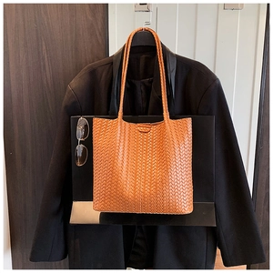 Detailed view of caramel brown woven leather tote bag texture and slim shoulder straps