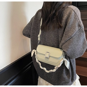 Detail of sage green crossbody bag with crocodile texture and silk scarf chain handle